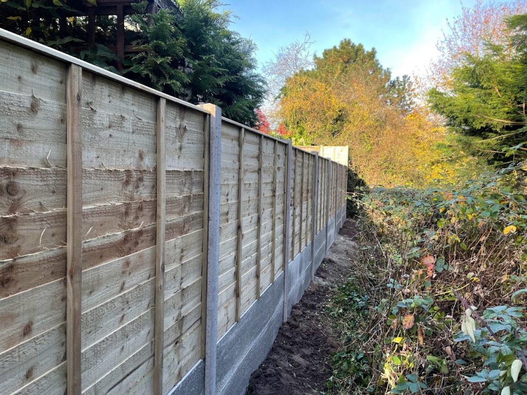 Waney Edge fence panels with concrete posts and twin gravel boards back view